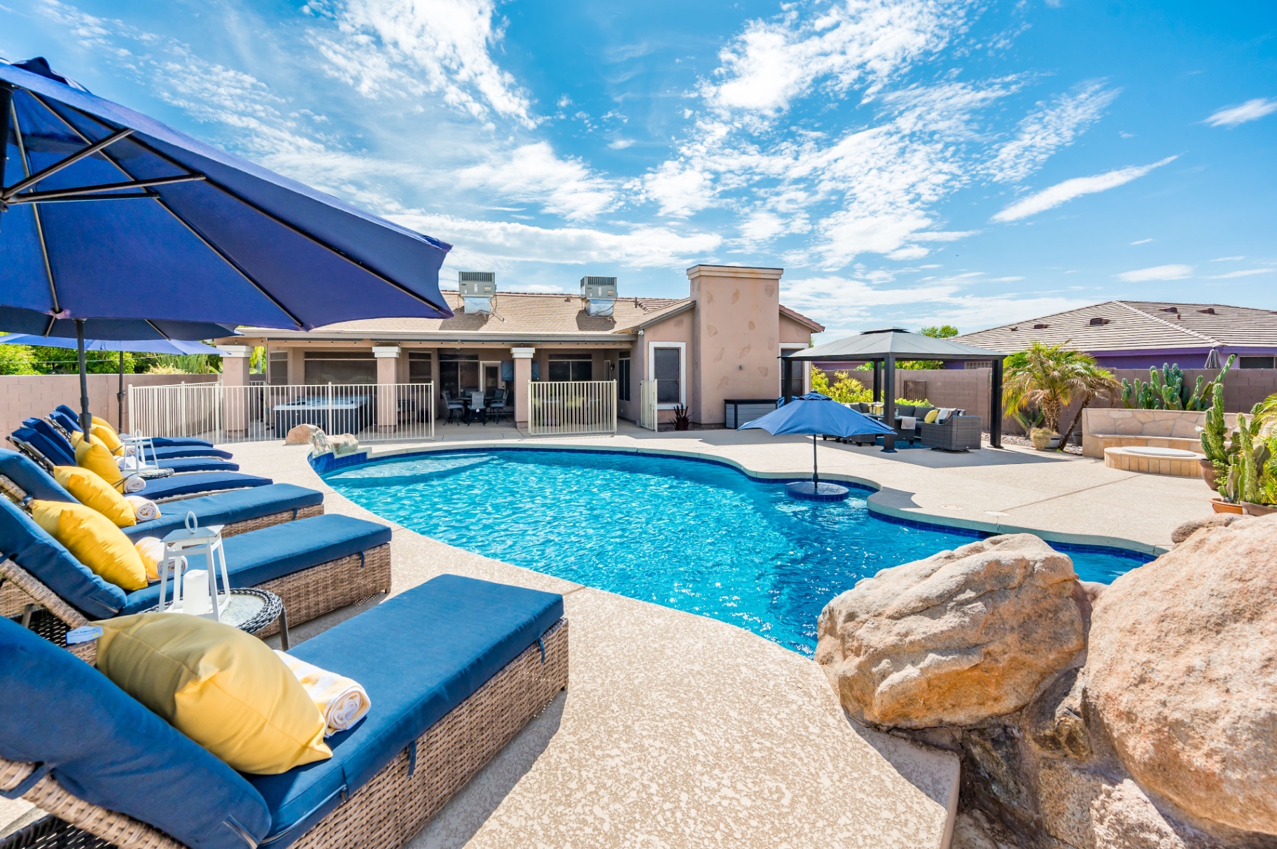 Backyard pool with blue loungers, umbrellas and gazebo