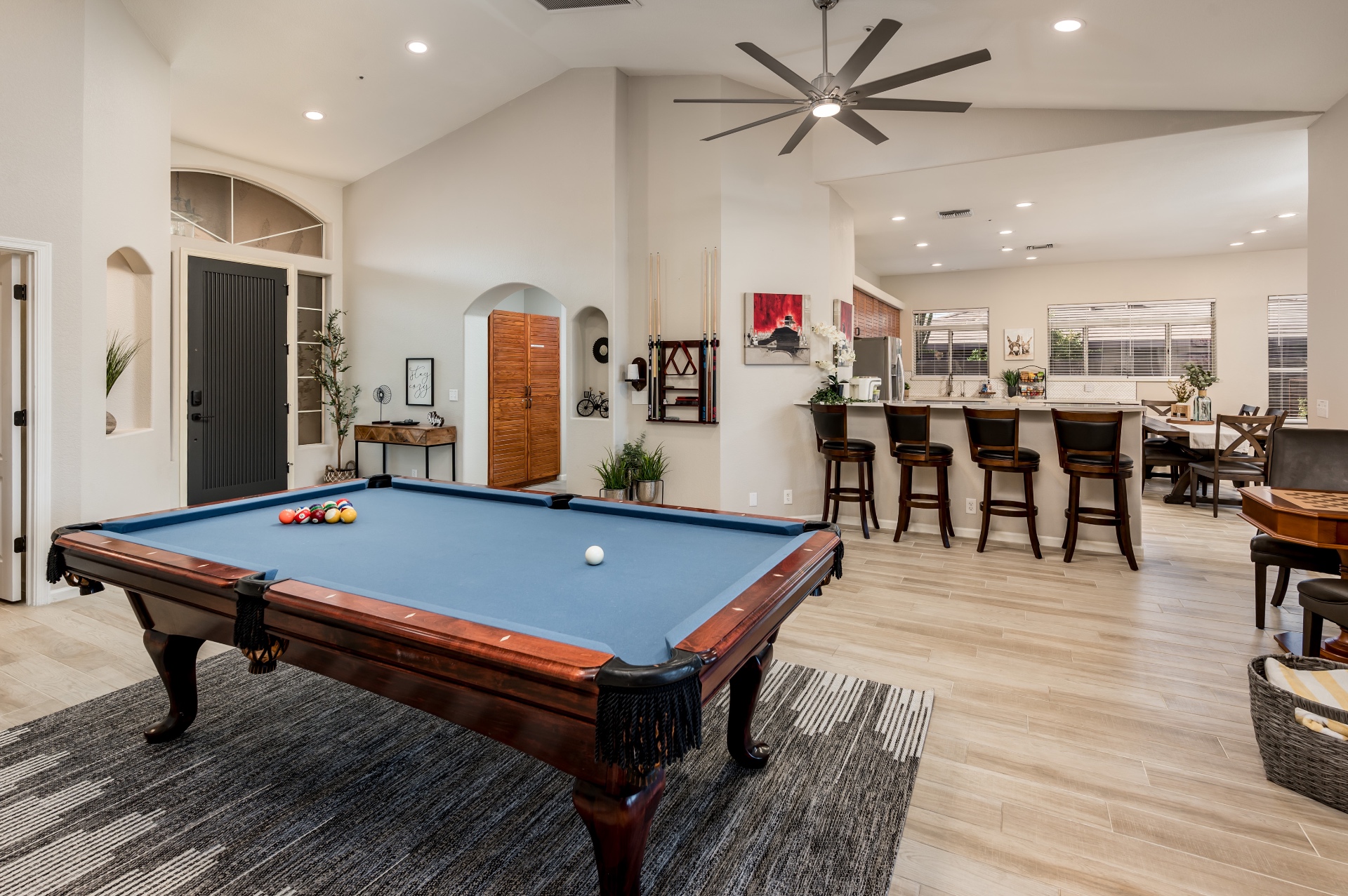 Open game room with blue-felt pool table, bar seating and dining area